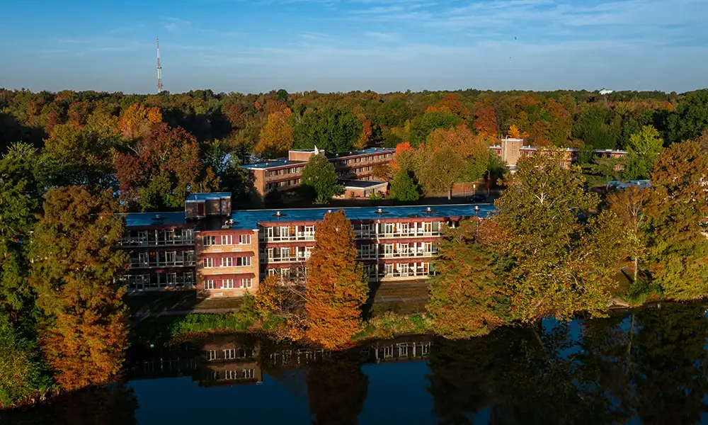 Aerial view of Southern Illinois University’s West Campus residence halls surrounded by colorful fall trees and reflected in the nearby lake.